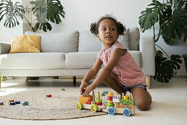 Girl kneeling and playing with toy vehicle at home