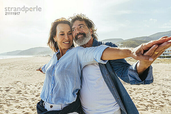 Happy senior couple enjoying vacations at beach on sunny day