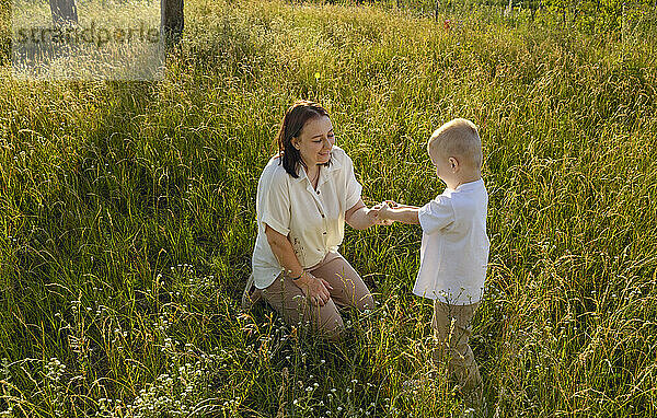 Mom and son communicate and laugh in a clearing in a city park.