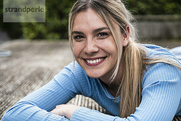 Smiling young woman lying on wooden patio