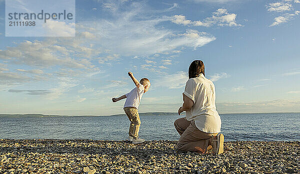 Mom and son spend time on the beach in the evening at sunset.