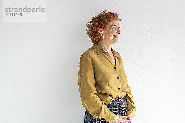 Happy redhead woman standing against white background