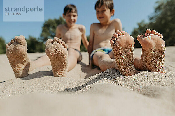 Happy sibling showing feet covered with sand