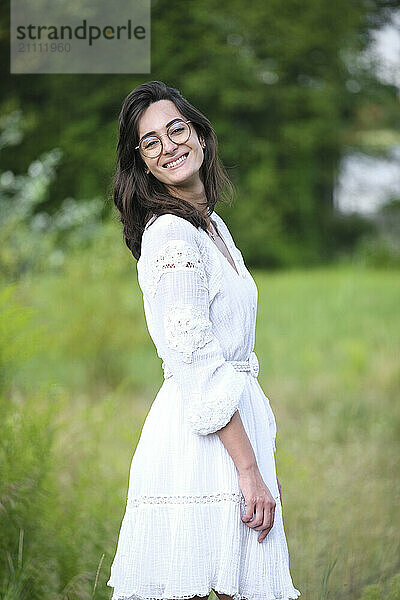 happy woman in white dress standing in meadow