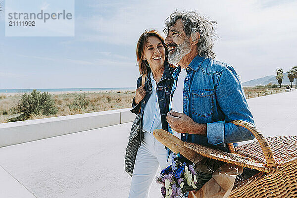 Cheerful senior couple with picnic basket on weekend