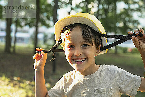 Happy boy wearing helmet in park