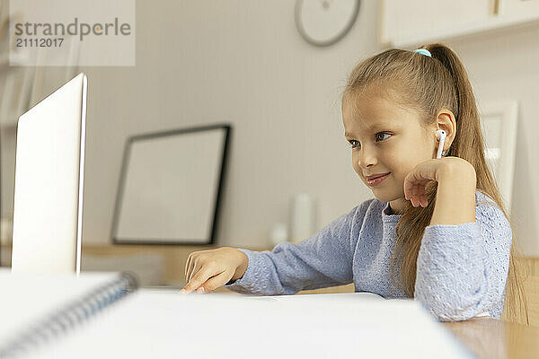 Happy girl scrolling on laptop at home