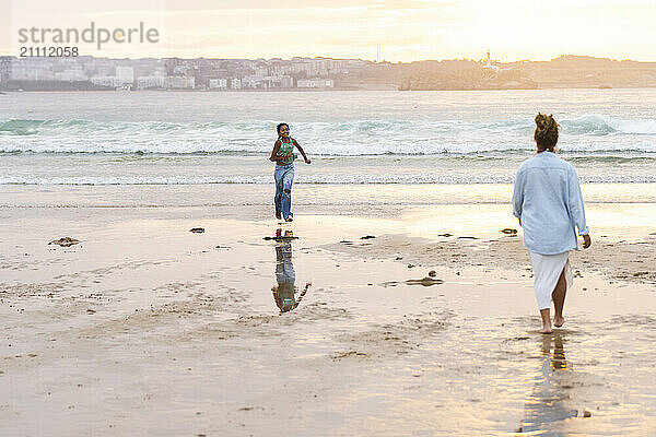 Girl running towards grandmother at beach