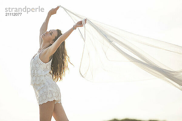 Carefree woman standing and holding cloth at beach