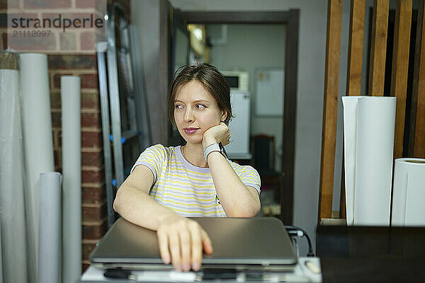 Businesswoman leaning on elbow near laptop in office