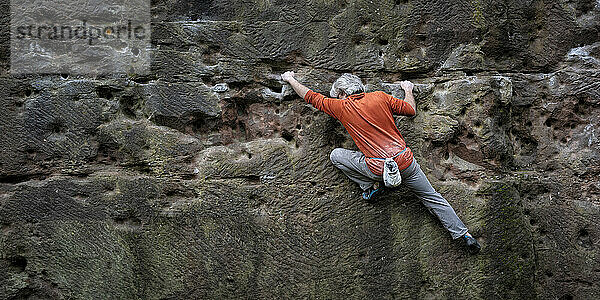 Mature man climbing rock