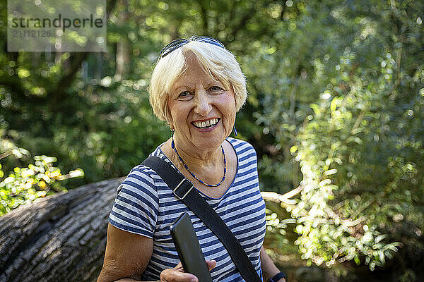 Senior woman in the Cetina valley  Dalmatia  Croatia  laughing and holding a smartphone.