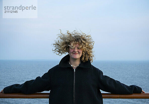 Girl with tousled hair wearing jacket under blue sky