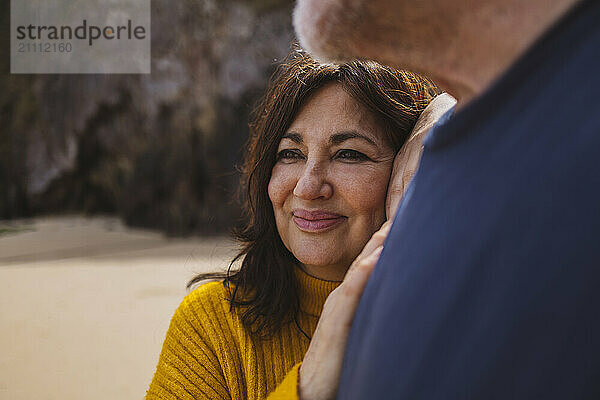 Happy senior woman leaning on man at beach