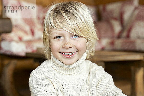 Happy blond boy sitting in chalet