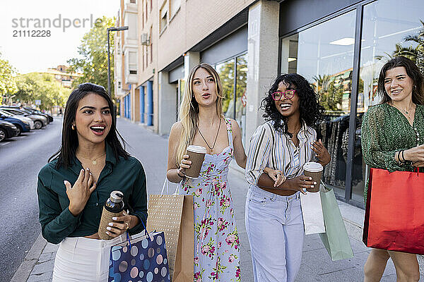 Happy woman with friends walking down street holding shopping bags