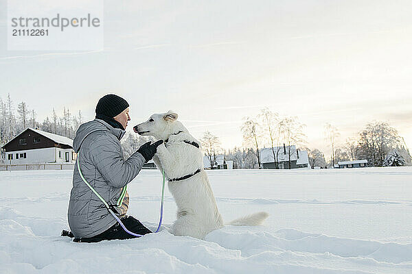 Man embracing sheepdog in snow