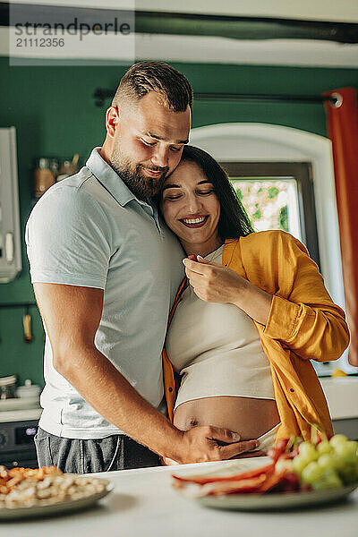 Affectionate man with pregnant wife in kitchen