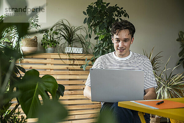 Young businessman using laptop sitting at home office