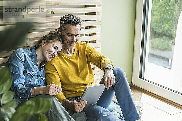 Couple sitting together on mattress using digital tablet