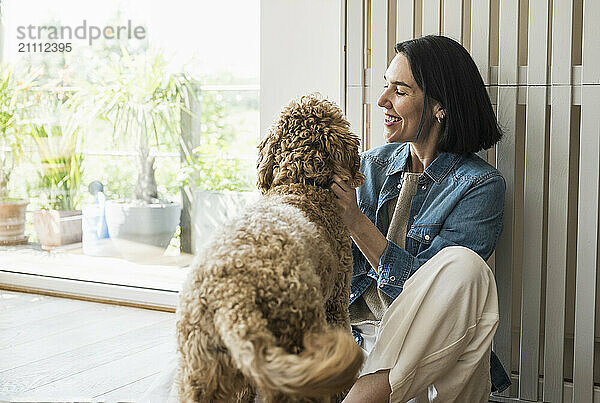 Smiling woman sitting with dog at home