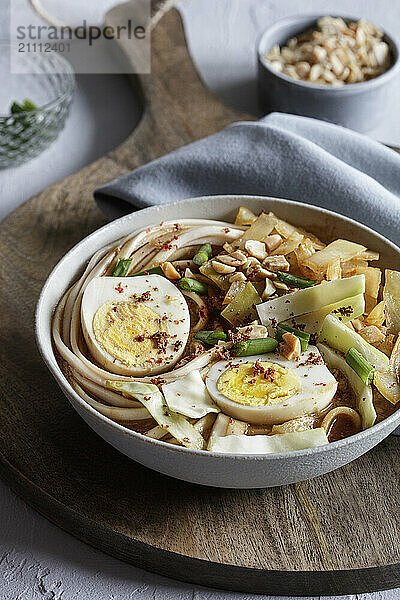 White cabbage soup with miso and udon noodles and boiled eggs and peanuts as topping