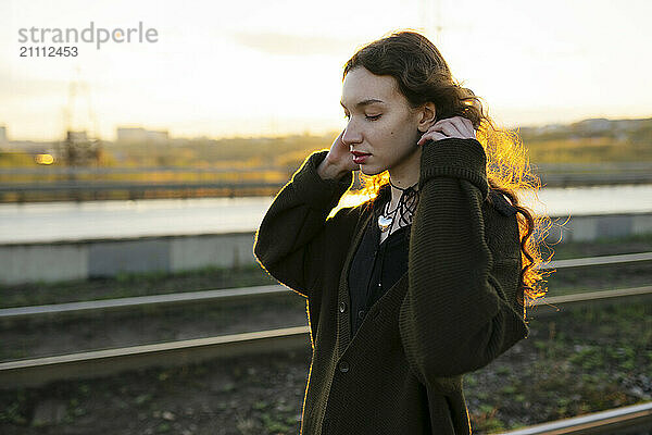 Young woman wearing headphones near railroad track