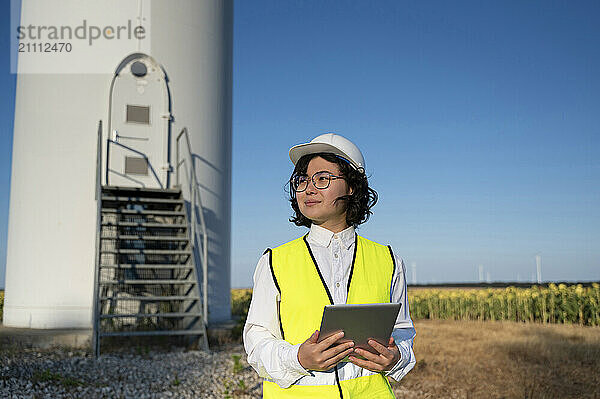 Engineer with reflective jacket holding tablet PC at wind farm