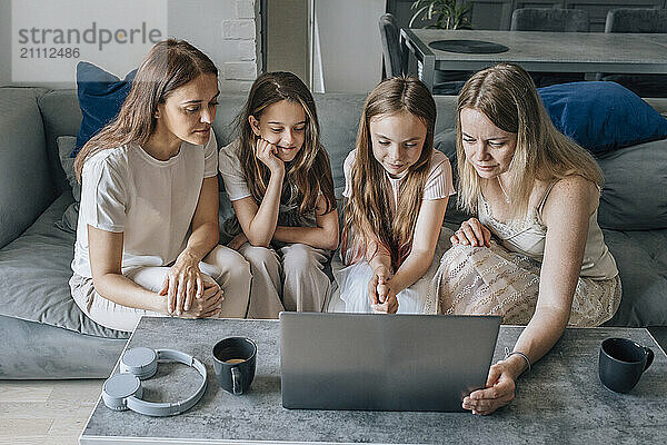 Friends using laptop with daughters at home