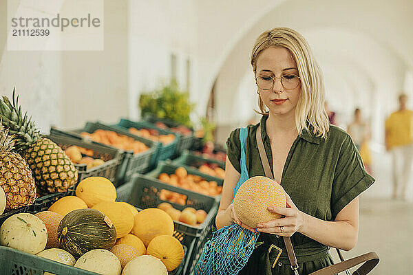 Woman examining melon at fruit stall