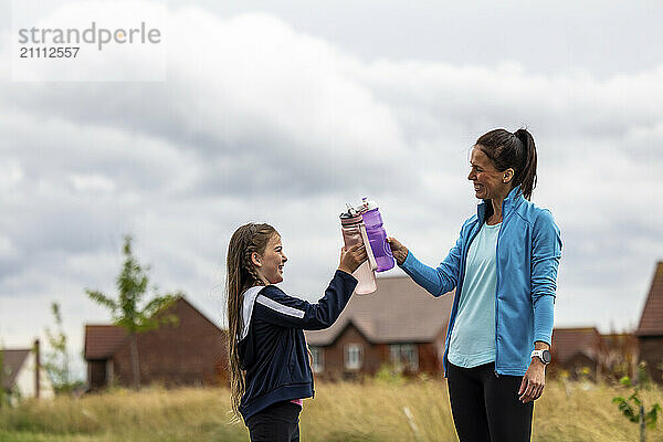 Mother and daughter toasting water bottles