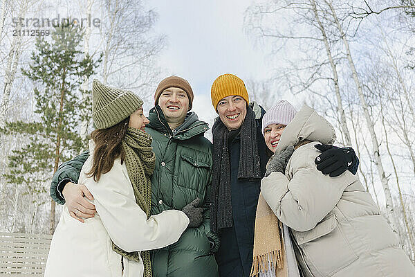 Happy friends with arms around enjoying vacation in winter