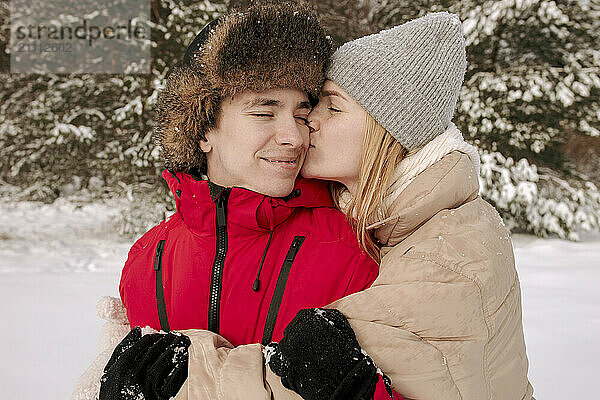 Affectionate woman kissing boyfriend in winter