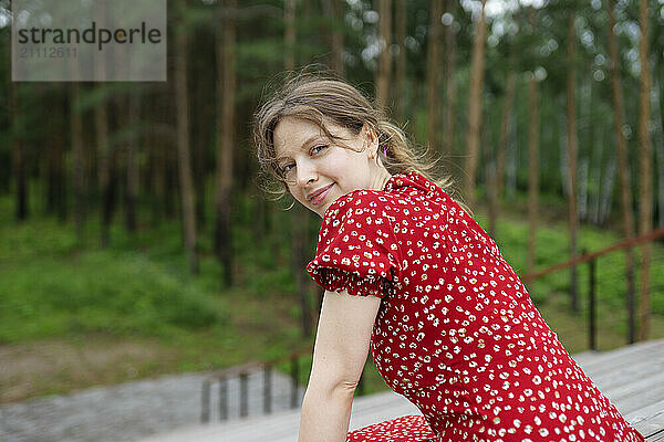 Smiling woman in red dress sitting on patio