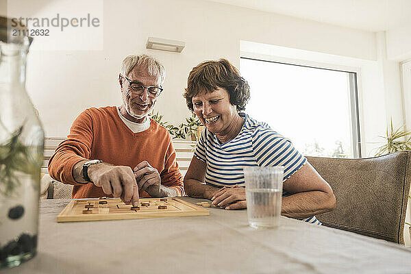 Senior couple enjoying board game on table at home