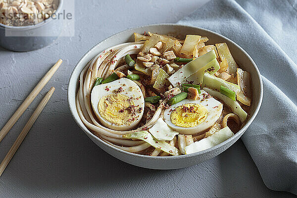 White cabbage soup with miso and udon noodles and boiled eggs and peanuts as topping