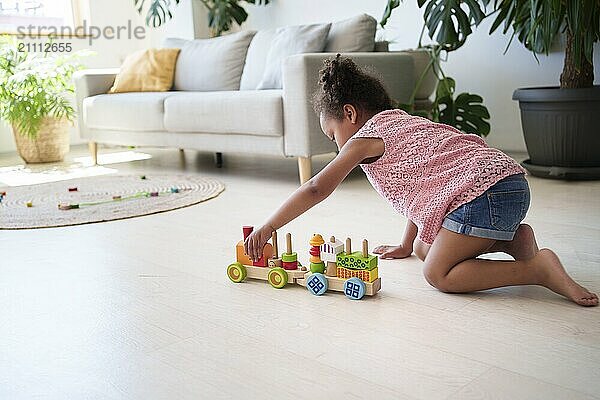 Girl playing with toy vehicle on flooring at home