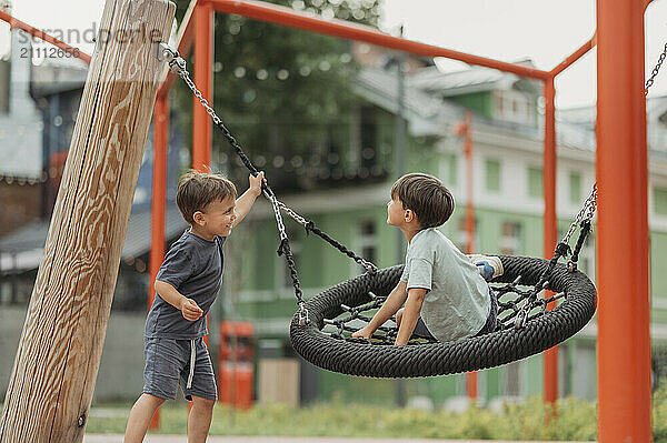 Happy brothers swinging on swing at park