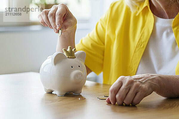 Senior woman saving money in piggy bank