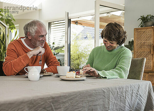 Happy couple eating coffee and cake in dining room