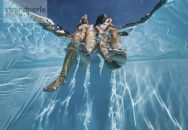 Friends sitting near pool with feet in water