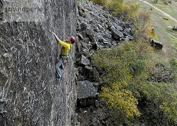 Rock climber wearing helmet and climbing rock mountain in Trowbarrow Quarry