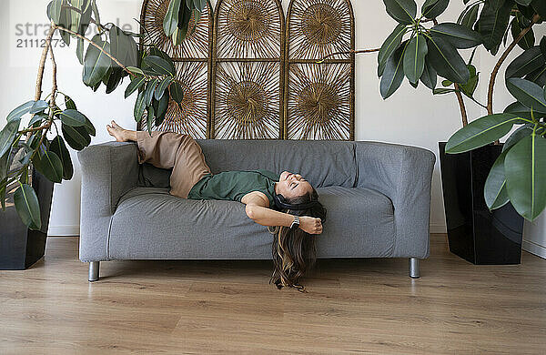 Relaxed woman lying on sofa at home