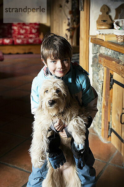 Boy holding dog and standing in chalet