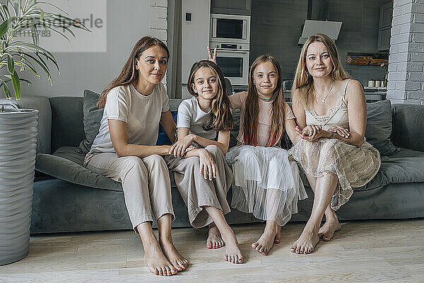 Smiling friends and daughters sitting together at home