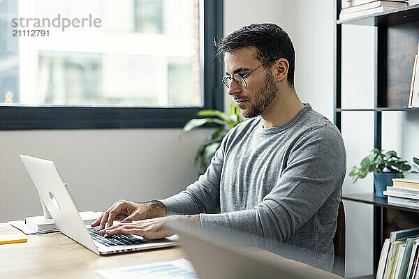 Focused businessman sitting and working on laptop in office