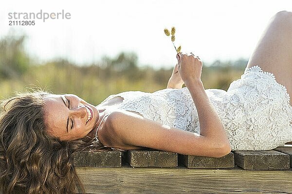 Smiling young woman holding pampas grass and lying down