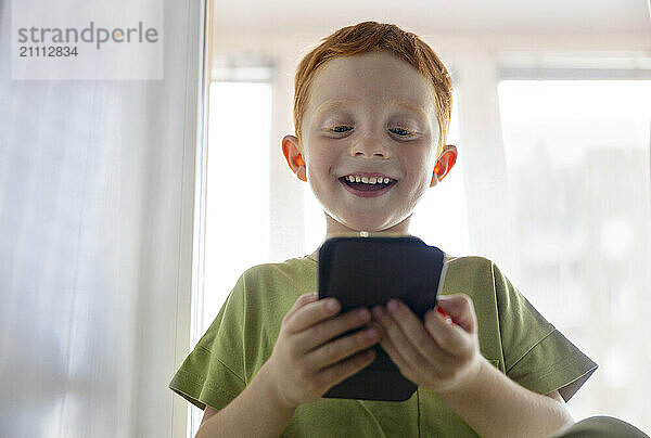 Happy boy using smart phone at home