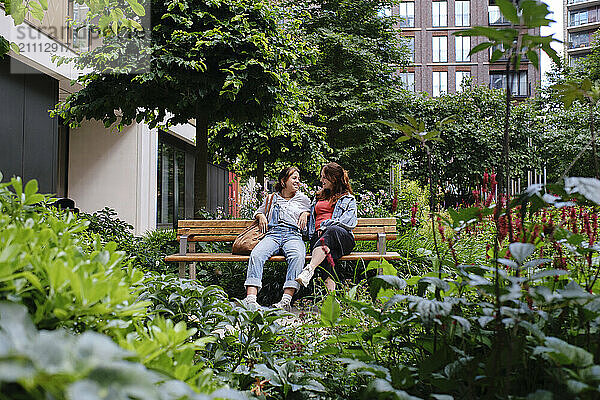 Young gay couple sitting on bench in park