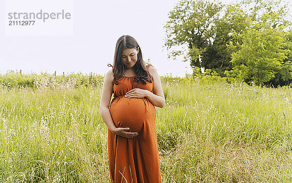 Pregnant woman standing in meadow